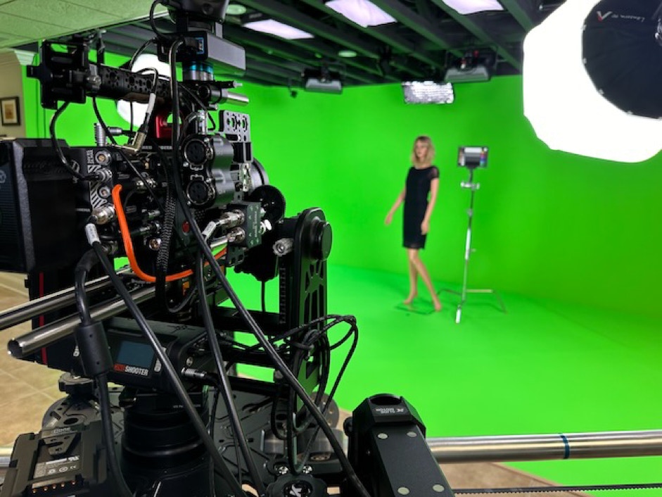 Red camera on a Kessler Crane Slider in front of a green screen